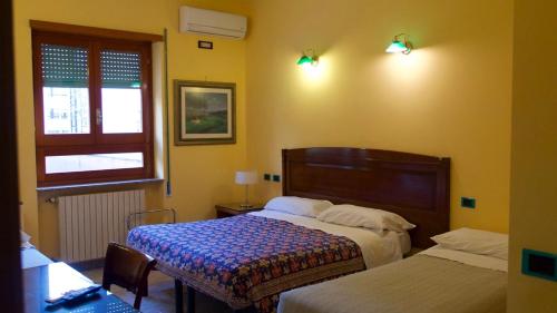 a bedroom with two beds and a table and a window at Hotel Benedetto in Rome