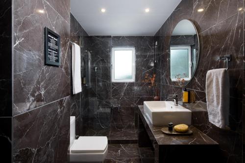 a black bathroom with a sink and a mirror at Athenian Riviera Hotel& Suites in Athens