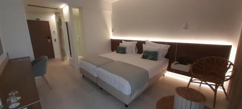 a bedroom with a bed and a desk and a chair at Porto Covo Praia Hotel & SPA in Porto Covo