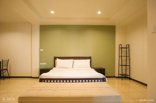 a bed in a room with a green wall at ดีลิฟวิ่ง เพลส มหาสารคาม in Maha Sarakham