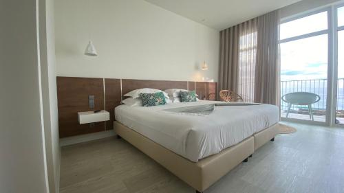 a bedroom with a large bed and a balcony at Porto Covo Praia Hotel & SPA in Porto Covo