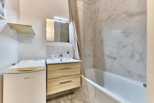 La salle de bains blanche est pourvue d'un lavabo et d'une baignoire. dans l'établissement Parc des Expositions et Tour Eiffel, à Paris