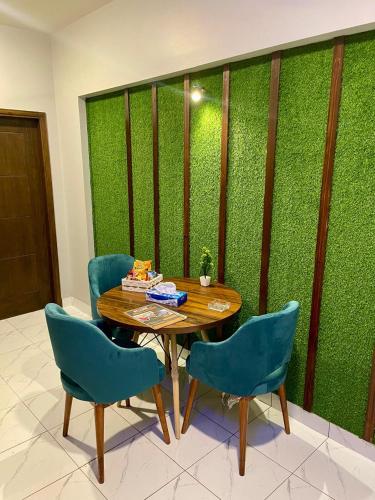 a table and chairs in front of a green wall at Beachfront Studios by Virani in Karachi
