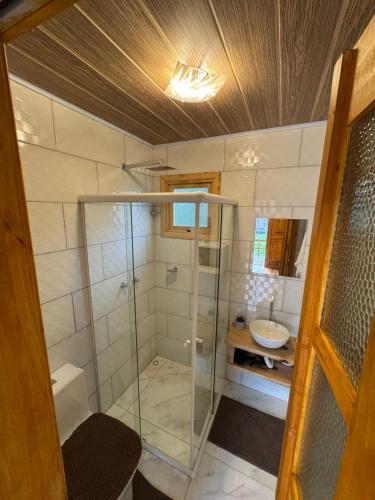 a bathroom with a glass shower and a sink at Paradouro da Serra Cabanas in Cambara do Sul