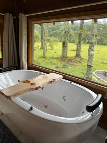 a white bath tub in a room with a window at Paradouro da Serra Cabanas in Cambara do Sul
