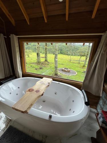 a bath tub in a room with a window at Paradouro da Serra Cabanas in Cambara do Sul