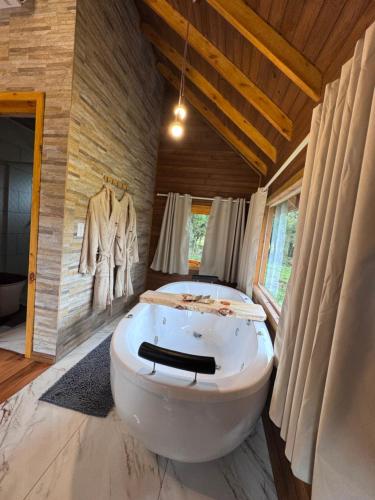 a bathroom with a large white tub in a room at Paradouro da Serra Cabanas in Cambara do Sul