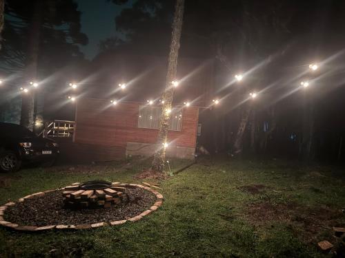 a fire pit in a yard at night with lights at Paradouro da Serra Cabanas in Cambara do Sul