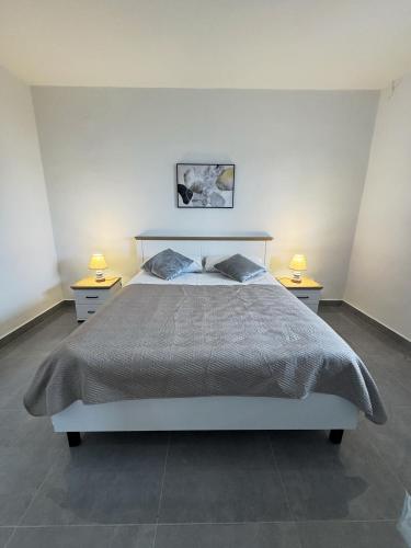 a bedroom with a bed with two nightstands and two lamps at ANKA - apartment by the sea in Kali