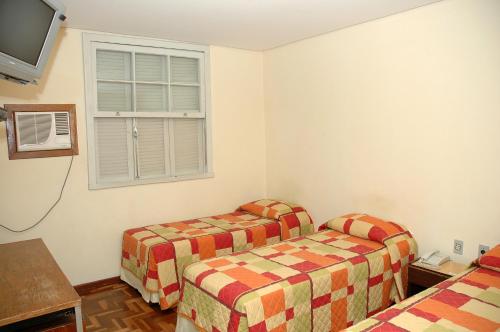 een kamer met twee bedden en een raam bij Hotel Porto Alegre in Porto Alegre