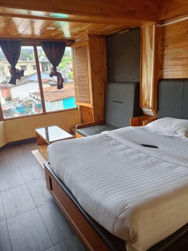 a bedroom with a large bed and a large window at HOTEL SHIV SHANTHI INN MOORTHI HOSPITALITY OOTy in Ooty