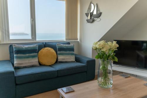 a blue couch in a living room with a vase of flowers at 7 Bedroom House in Woolacombe - Sleeps 12 in Woolacombe