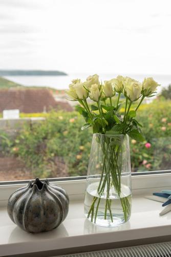 a vase filled with white flowers sitting on a window sill at 7 Bedroom House in Woolacombe - Sleeps 12 in Woolacombe