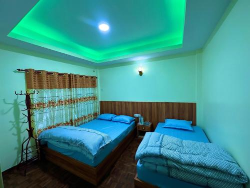 two beds in a room with a green ceiling at Dorje Homestay in Kathmandu