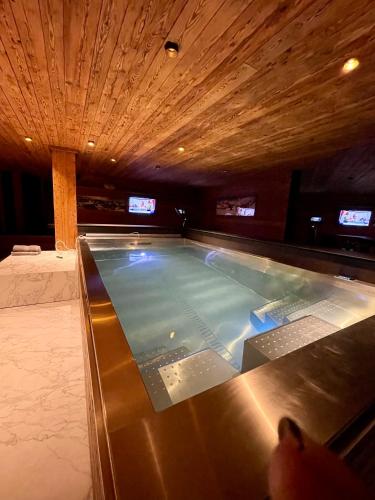 a large swimming pool in a room with televisions at Chalet Les Moulins 5 chambres cheminée piscine sauna parking privé in Verbier