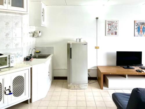 a white kitchen with a refrigerator and a tv at Impact Arena Condo C1 by GoodRoom24 in Ban Song Hong