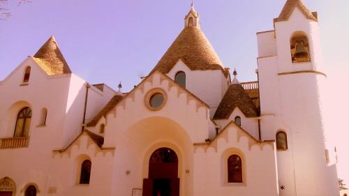 a white church with a steeple and a tower at Miratrulli Apartment & Trullo dell'Aia in Alberobello