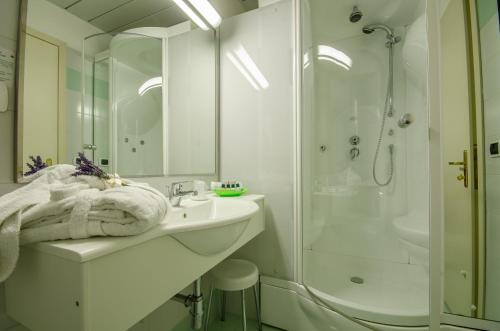 a white bathroom with a sink and a shower at Hotel Ovidius in Sulmona