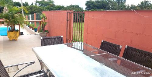 a patio with a table and chairs next to a red wall at Temporada Belas Casas in São Pedro
