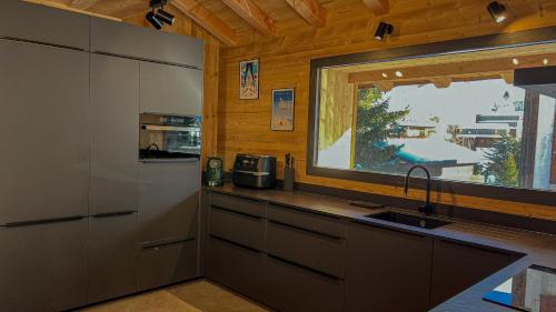une cuisine avec un évier et une fenêtre dans l'établissement Chalet Loune, à Les Deux Alpes