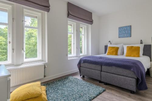 a bedroom with a bed and two windows at Hotel Oranjestaete in Nijmegen