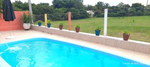 a swimming pool with potted plants on a fence at Temporada Belas Casas in São Pedro