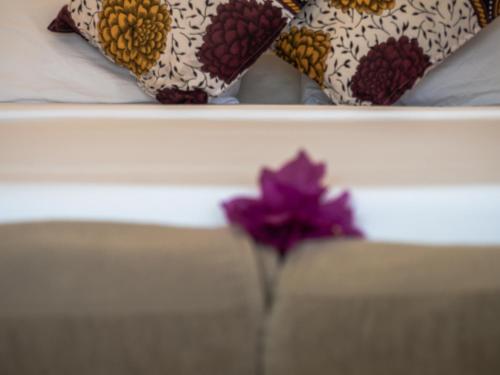 a purple flower in a vase on a bed at Pingwe Beach Apartments in Pingwe