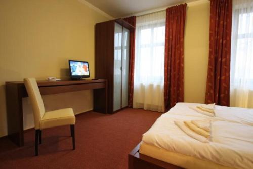 a hotel room with a bed and a desk with a computer at Penzion Haydnuv Dum in Dolní Lukavice