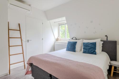 a bedroom with a bed with blue pillows and a ladder at Hotel Oranjestaete in Nijmegen