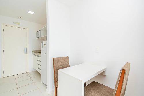 a white kitchen with a white table and chairs at Vision Hotel em Brasília 60613 in Brasilia