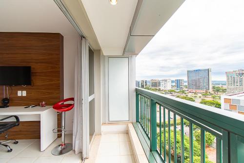 a room with a desk and a balcony with a view at Vision Hotel em Brasília 60613 in Brasilia