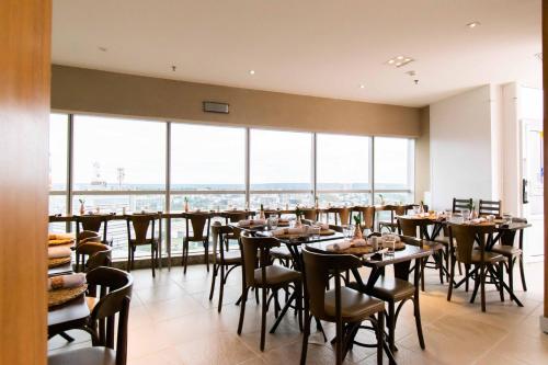 a dining room with tables and chairs and large windows at Vision Hotel em Brasília 60613 in Brasilia