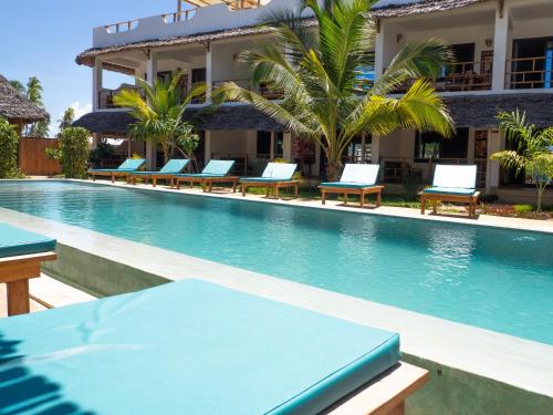 a swimming pool with lounge chairs in front of a building at Pingwe Beach Apartments in Pingwe