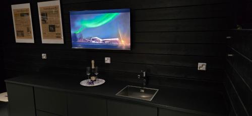 a bathroom with a sink and a tv on a wall at Riverside villa with sauna and jacuzzi in Rovaniemi
