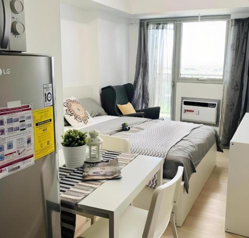a room with a bed and a table and a refrigerator at Dtravellers Home 1 at AZURE NORTH BALI Tower in San Fernando