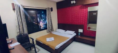 a bedroom with a bed and a desk and a window at Arihant palace in Shirdi