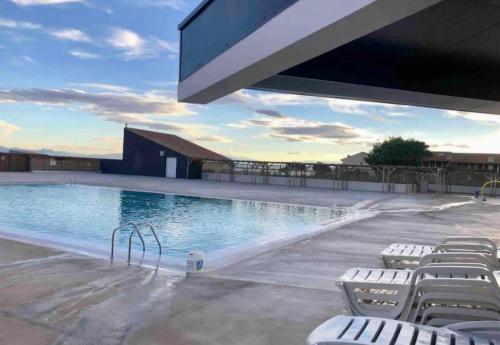 une grande piscine entourée de chaises blanches. dans l'établissement T3 terrasse et piscine, au Barcarès