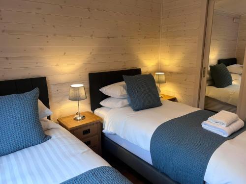 a bedroom with two beds and a mirror at Dovestone Luxury Lodges sleeps 4 - pets welcome in Oldham