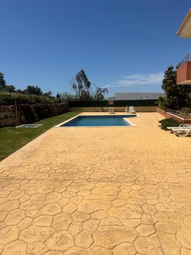 a swimming pool in a yard with a stone patio at Jardins da guia in Albufeira