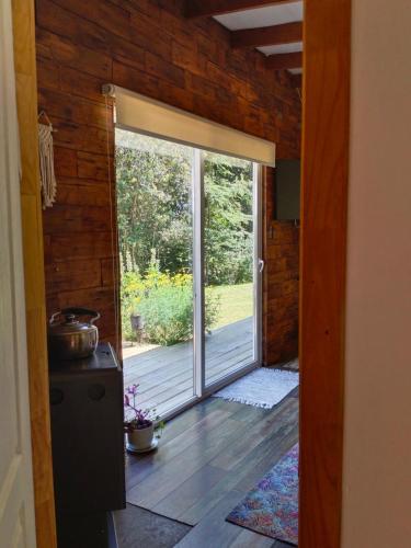 an open door to a patio with a sliding glass door at Acogedora cabaña en el bosque, acceso vehiculos 4x4 in Cochamó