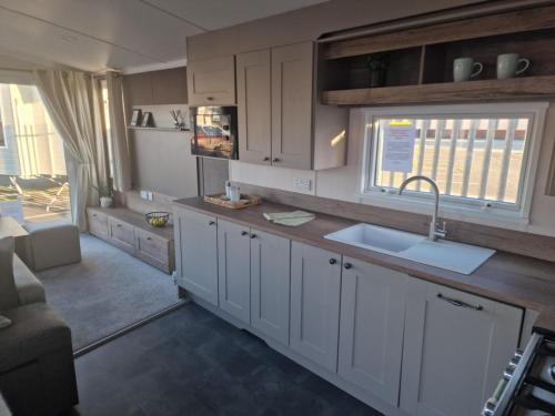 a kitchen with white cabinets and a sink at Serenity - Luxury Hot Tub, Sunnymede, Fantasy Island, , Ramped Access, Parking, Dog Friendly in Ingoldmells