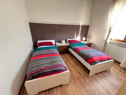 two twin beds in a room with a window at Villa Gianfranca - sentiti come a casa in Corno di Rosazzo