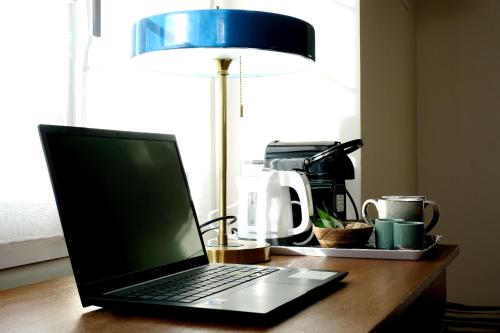 einem Laptop auf einem Schreibtisch neben einer Lampe in der Unterkunft Chambres d'hôtes de charme LE LOGIS ROUGE la Rochelle, Vendée, Ile de Ré, Marais Poitevin, calme mer campagne piscine in Charron