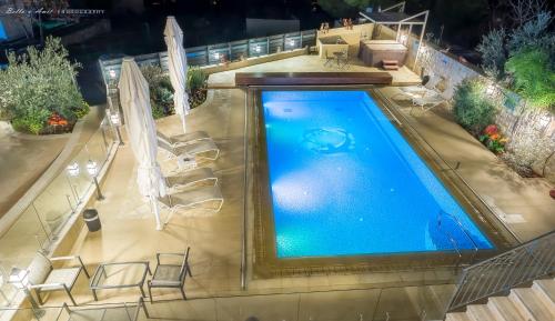 an overhead view of a swimming pool with chairs and umbrellas at Villar in Rosh Pinna