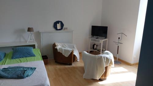 a bedroom with a bed and a chair and a television at L'Eclose in Le Guilvinec