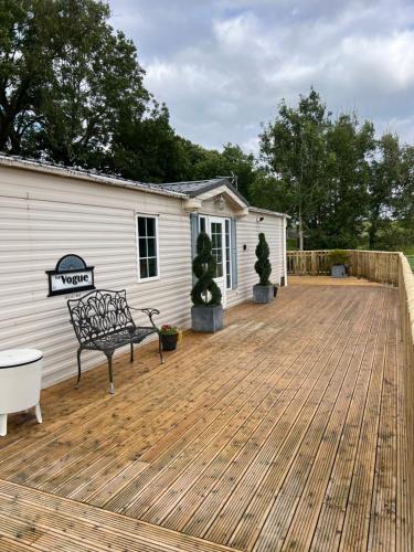 a patio with a bench on a wooden deck at The Vogue Lodge in Buxton