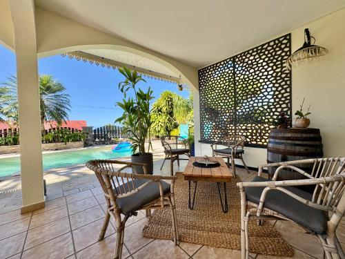 a patio with chairs and a table and a pool at Villa Palm Eden in Saint-Louis