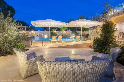 a patio with chairs and tables and umbrellas at night at Villar in Rosh Pinna