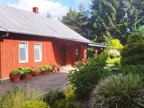 a red house with potted plants in front of it at Agroturystyka Pod Gruszą in Chyrowa