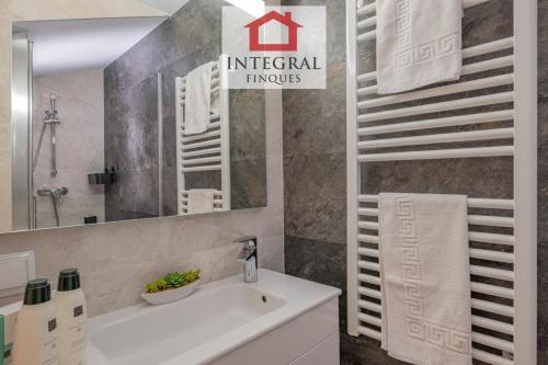 een badkamer met een witte wastafel en een spiegel bij L'Àtic de Palamós in Palamós